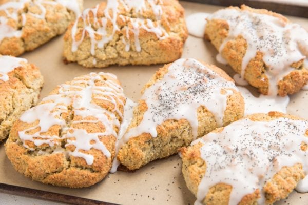 Scones on a baking sheet fresh out of the oven with a lemon glaze on top.