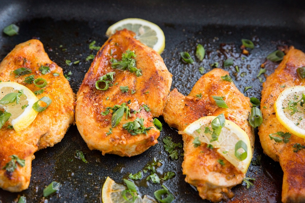 horizontal photo of chicken breasts in a casserole dish fresh out of the oven.