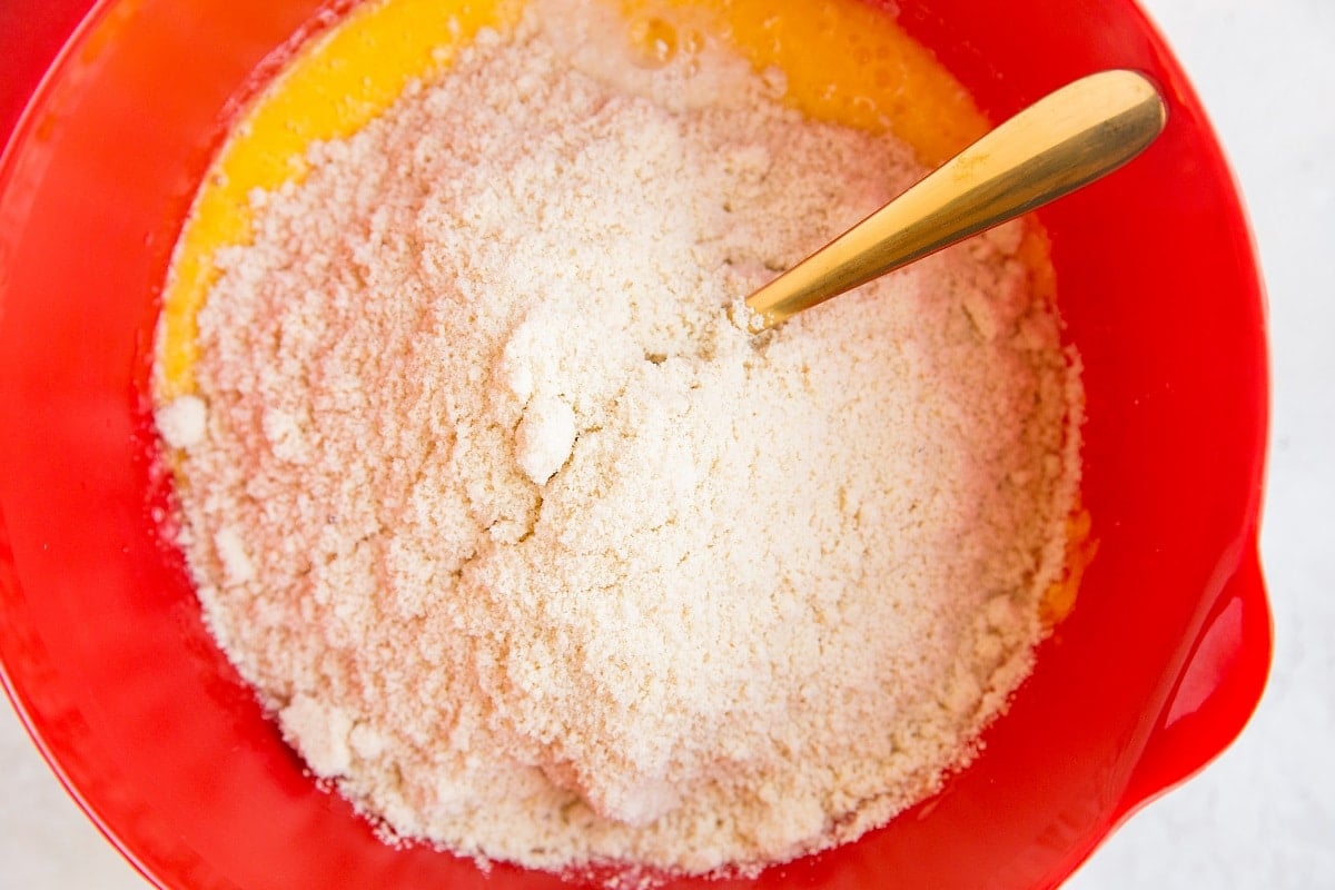 Mixing bowl with the wet ingredients mixed up and dry ingredients on top.