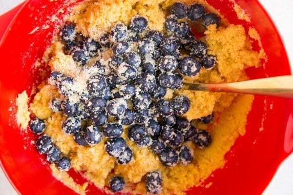 Cake batter in a mixing bowl with blueberries