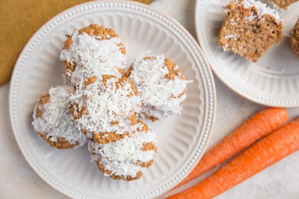 horizontal top down image of muffins on plates with carrots and a napkin to the side