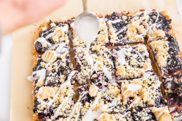 Cherry pie bars being drizzled with glaze.