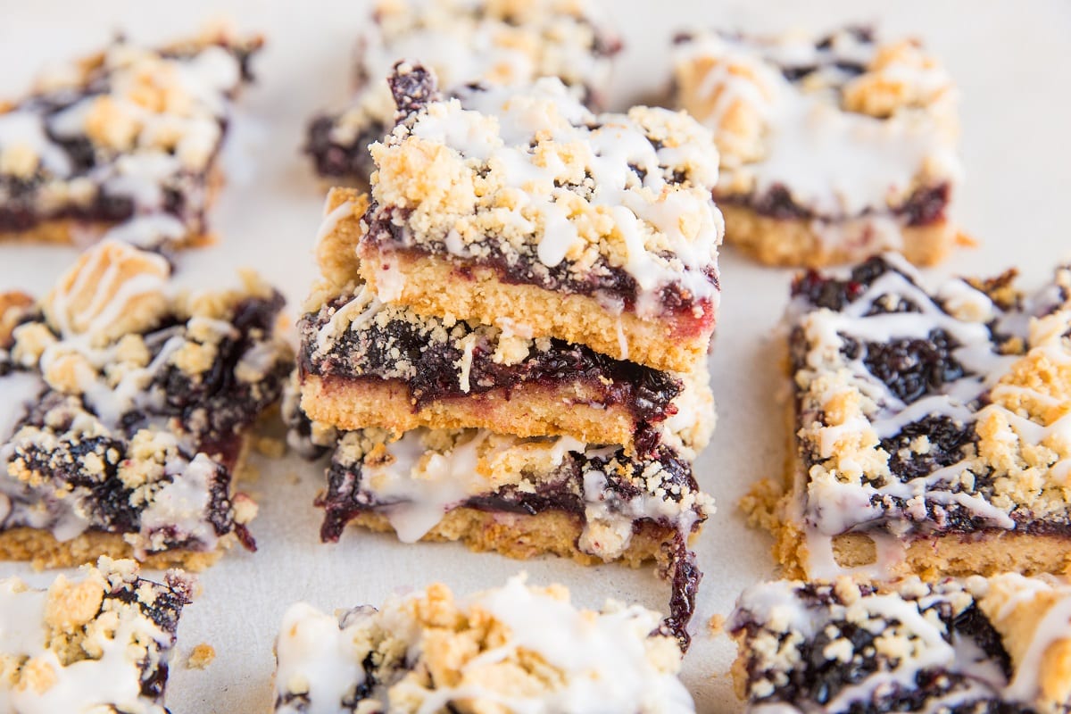horizontal photo of a stack of cherry pie bars with several cherry pie bars around the stack.