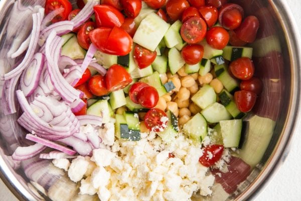 Ingredients for Mediterranean garbanzo bean salad in a large bowl.