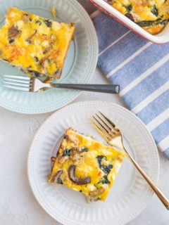 two plates with two slices of sausage and mushroom breakfast casserole with a blue striped napkin to the side.