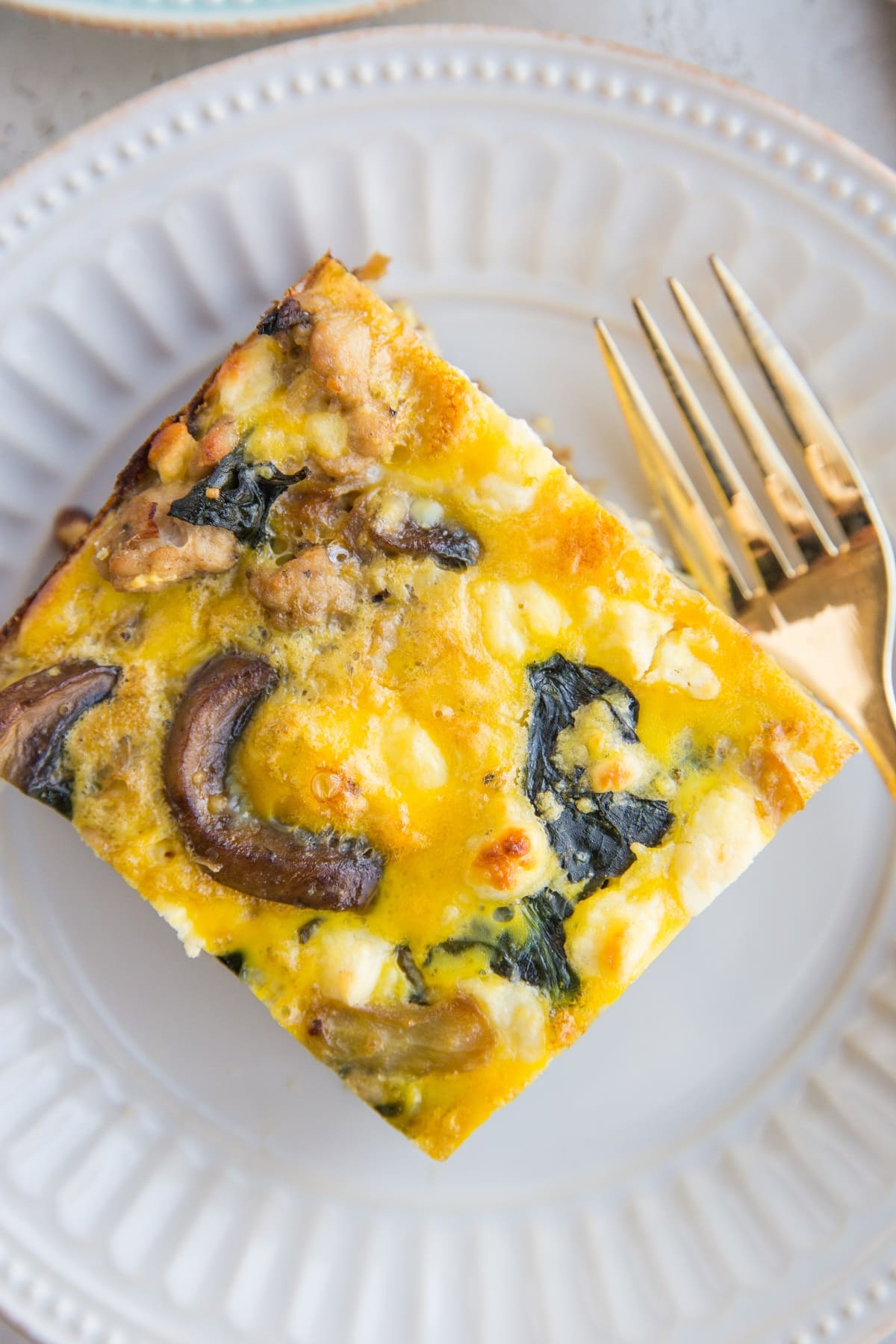 close up top down photo of mushroom and sausage breakfast casserole on a white plate
