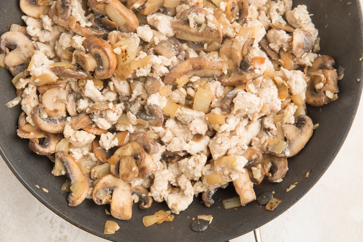 Sausage, onion, garlic, and mushrooms cooking in a skillet