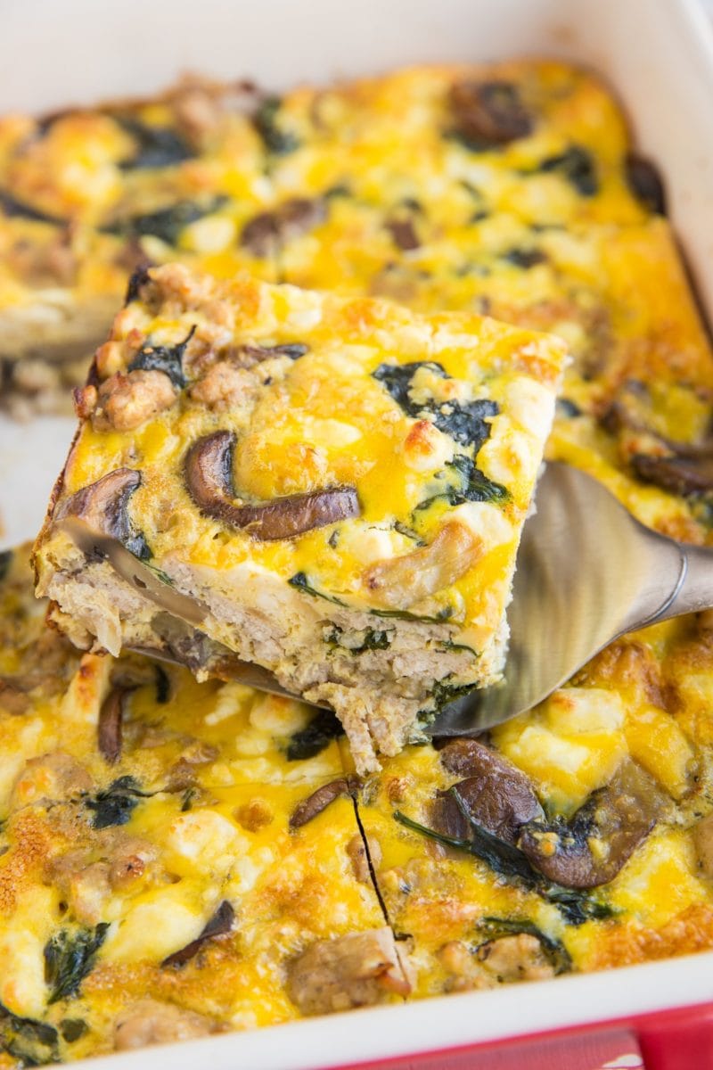 Casserole dish of mushroom sausage casserole cut into slices with one slice lifted out