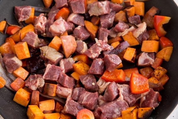 Steak, potatoes, and bell pepper cooking in a skillet