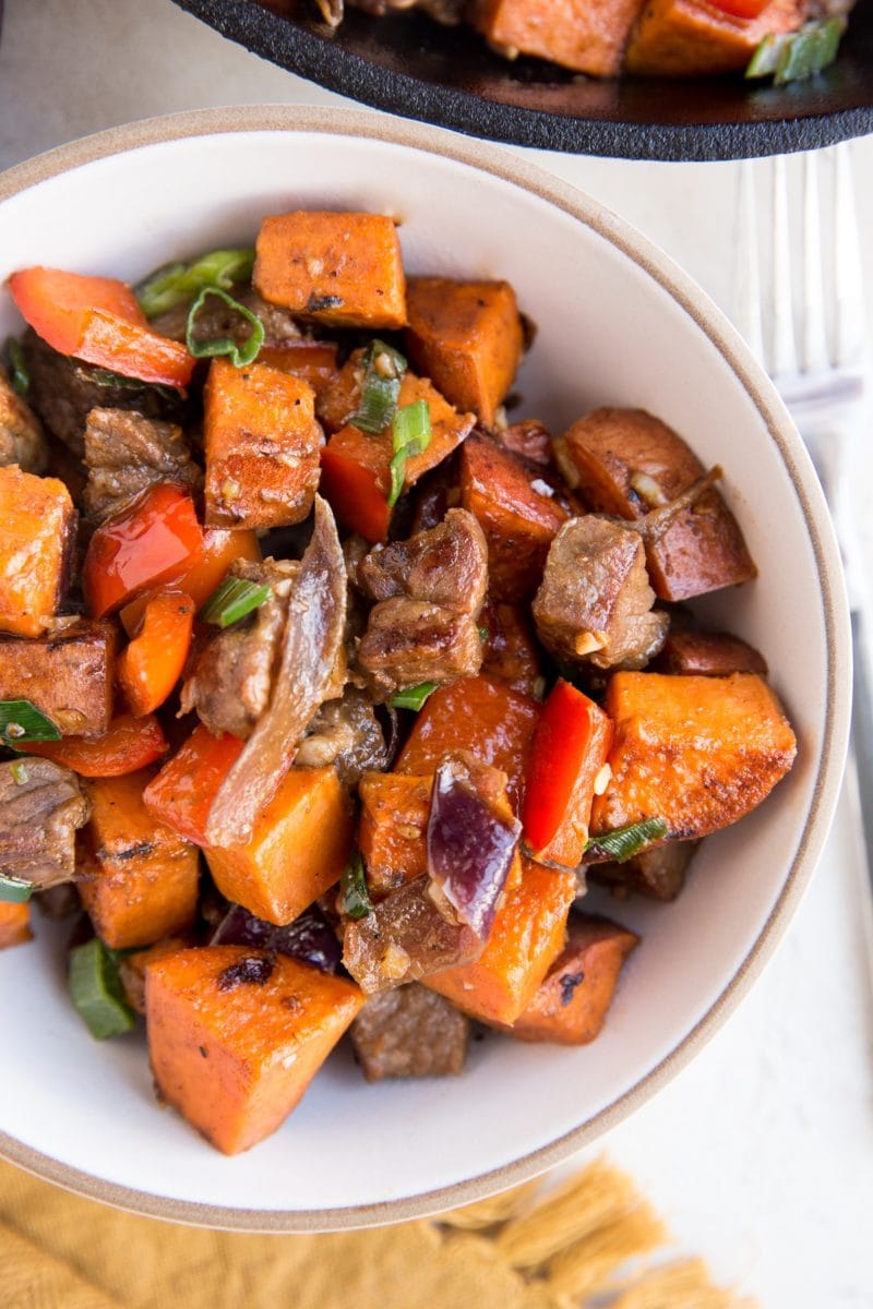 Big bowl of steak bites and sweet potatoes with a fork and a napkin