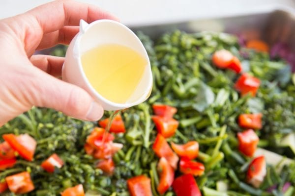 Pouring avocado oil over raw vegetables