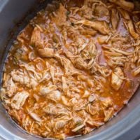 Crock pot full of shredded Mexican chicken for tacos, burritos, enchiladas, and more.