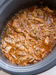 Crock pot full of shredded Mexican chicken for tacos, burritos, enchiladas, and more.