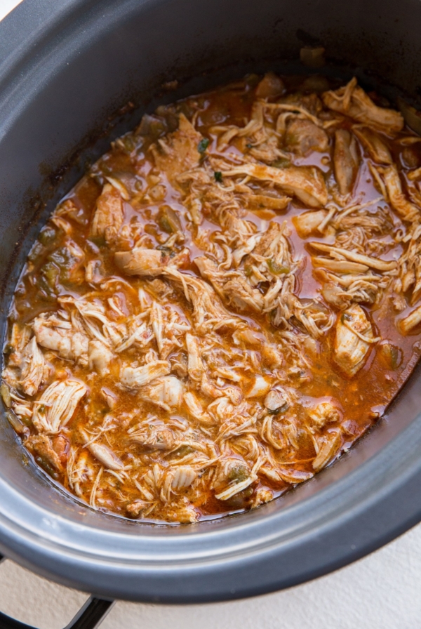 Crock pot full of shredded Mexican chicken for tacos, burritos, enchiladas, and more.