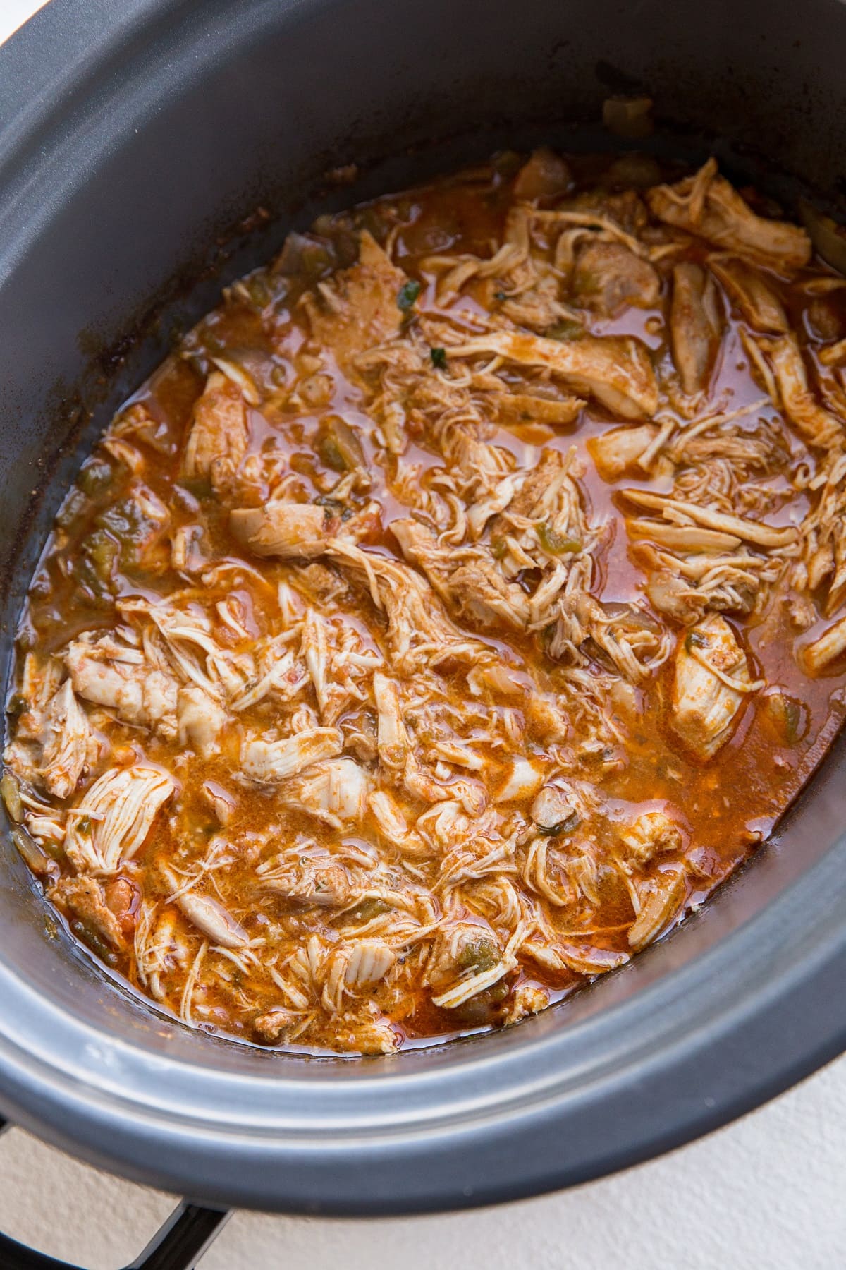 Crock pot full of shredded Mexican chicken for tacos, burritos, enchiladas, and more.