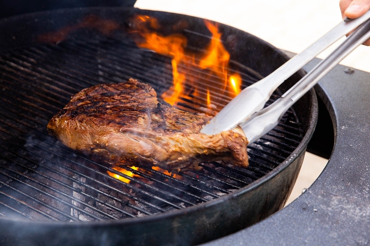 flipping a grilled tri tip with tongs