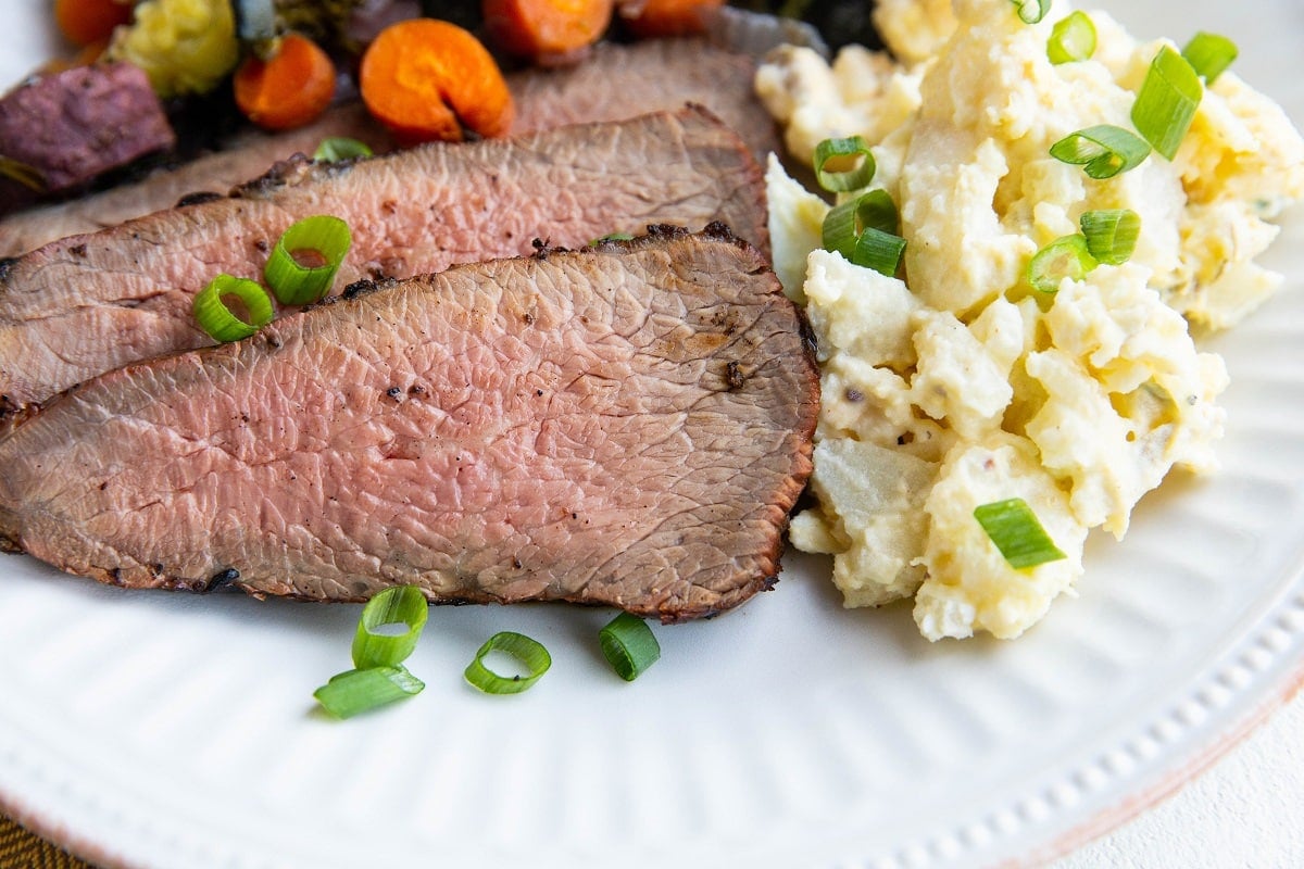 horizontal image of plate of grilled tri tip with side dishes