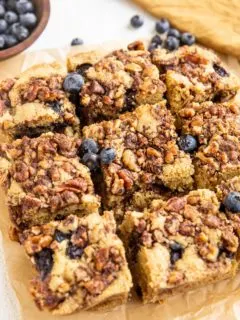 Slices of gluten-free coffee cake on a piece of parchment paper with blueberries to the side.