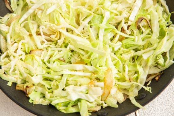 Skillet with onion and cabbage cooking