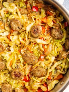 cabbage and fresh vegetables with sausage in a skillet.
