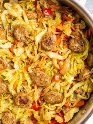 cabbage and fresh vegetables with sausage in a skillet.
