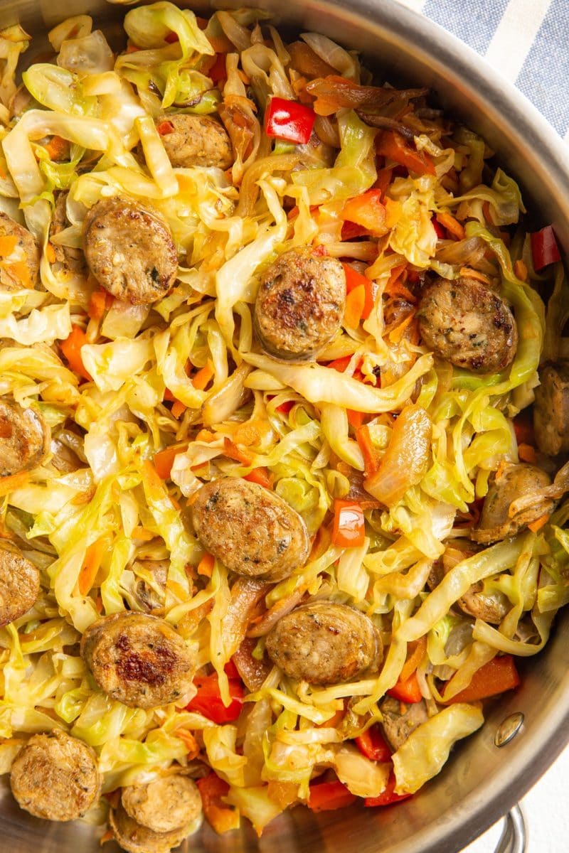 cabbage and fresh vegetables with sausage in a skillet.