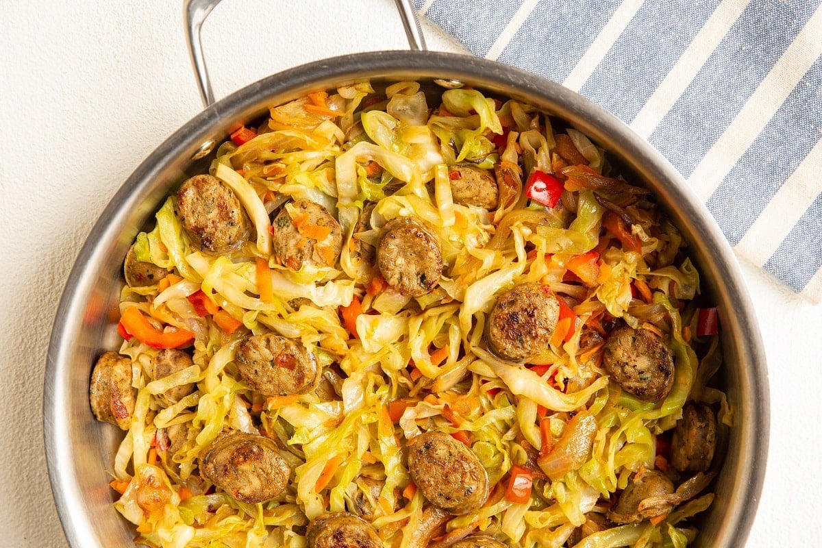 stainless steel skillet with fresh cooked vegetables and sausage