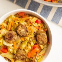 bowl of sausage and cabbage with a skillet of sausage and cabbage