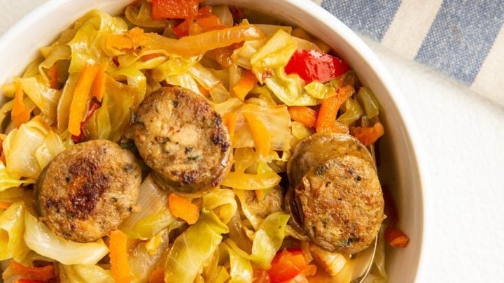 bowl of sausage and cabbage with a skillet of sausage and cabbage