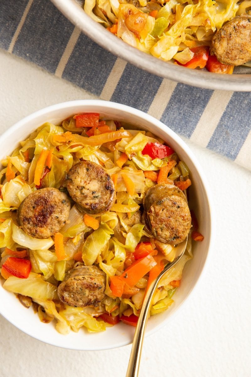 bowl of sausage and cabbage with a skillet of sausage and cabbage