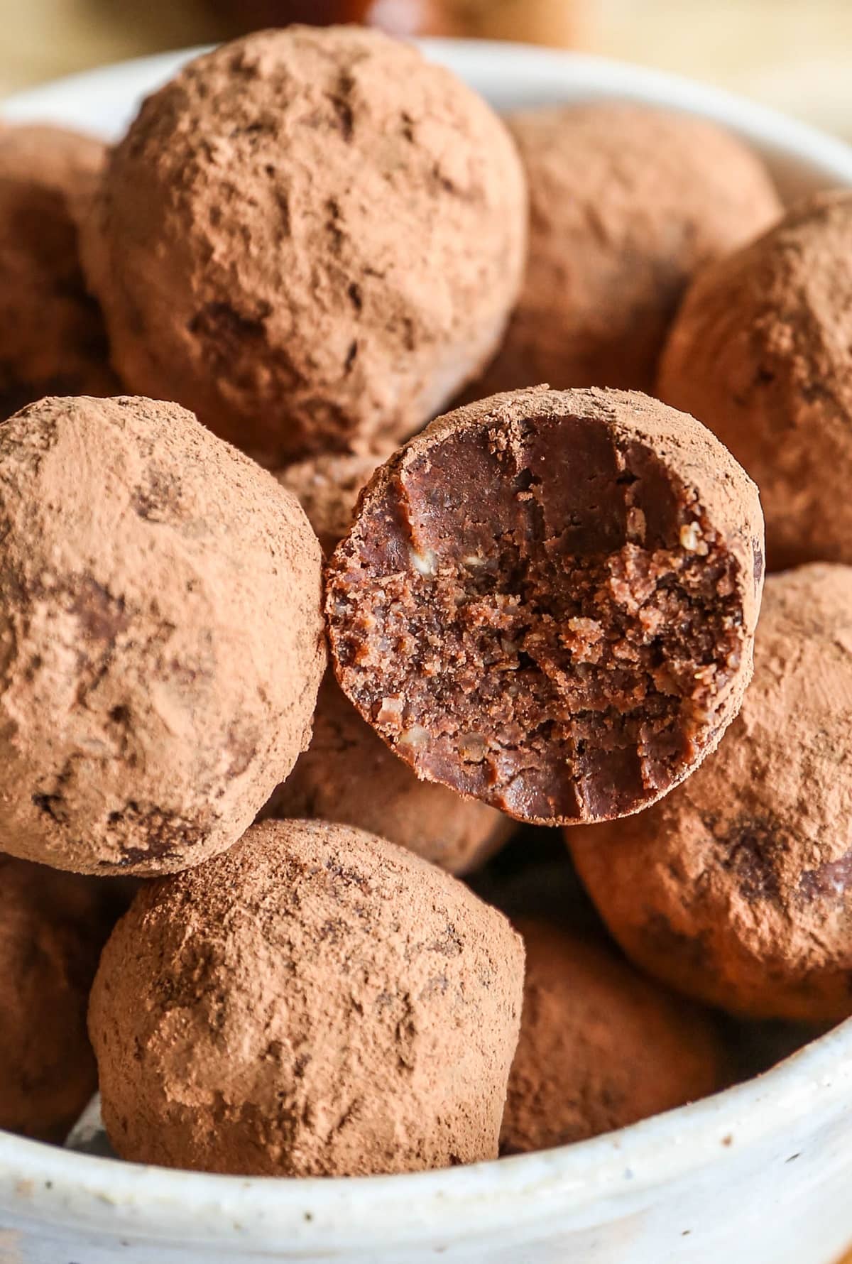 Bowl of chocolate date energy bites with one of the balls with a bite taken out.