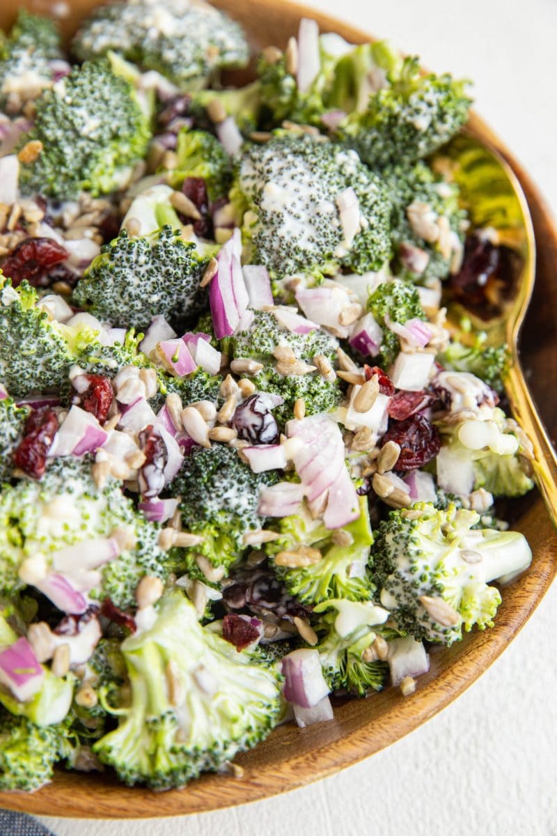 classic broccoli salad in a wooden bowl with golden spoon.