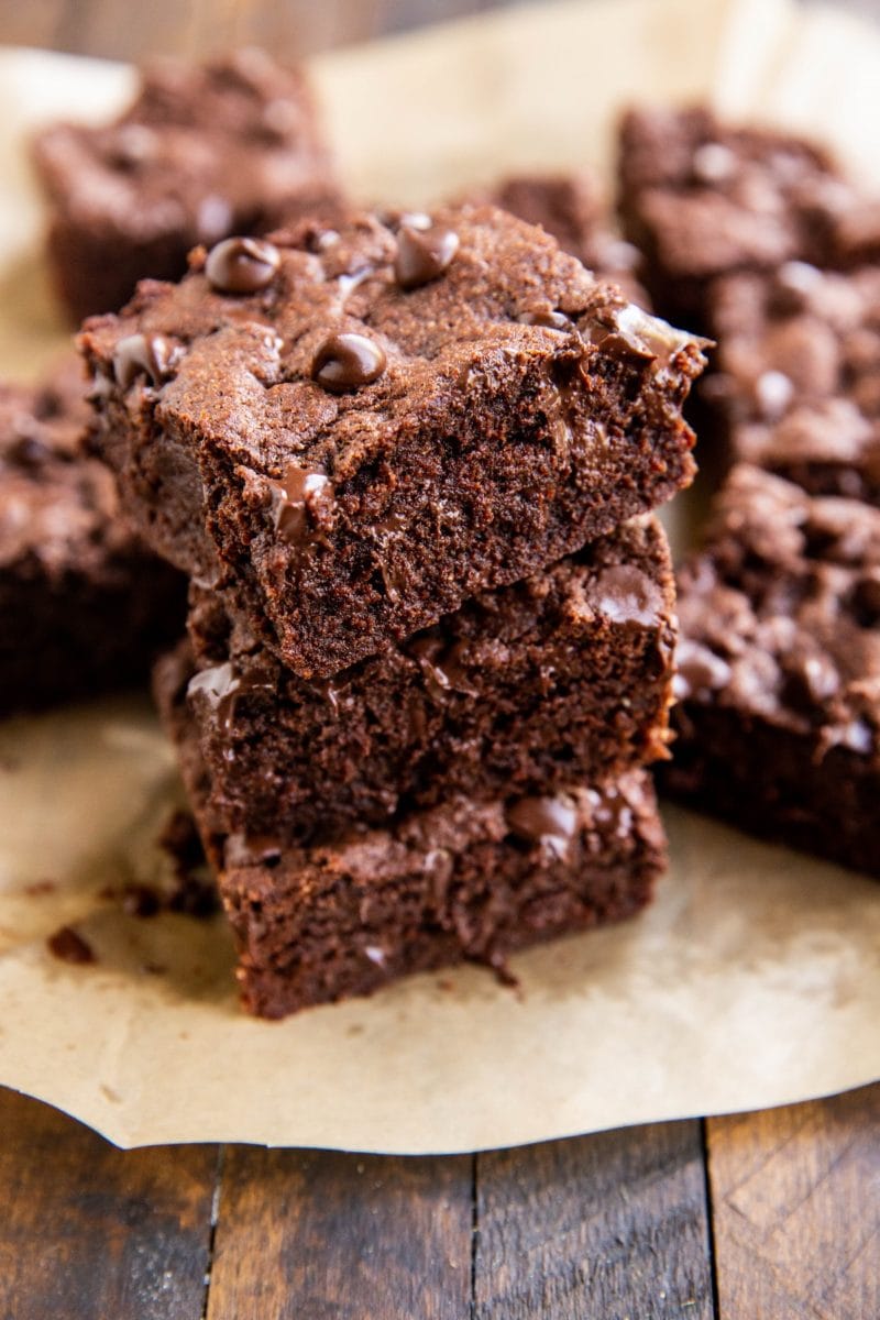 Stack of brownies on a sheet of parchment paper.