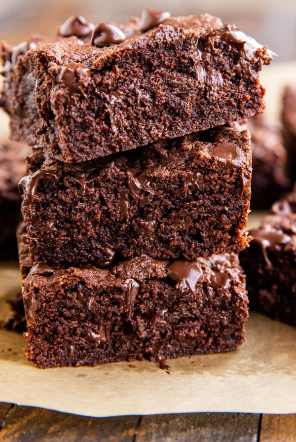 Stack of three coconut flour brownies with gooey chocolate shining through.