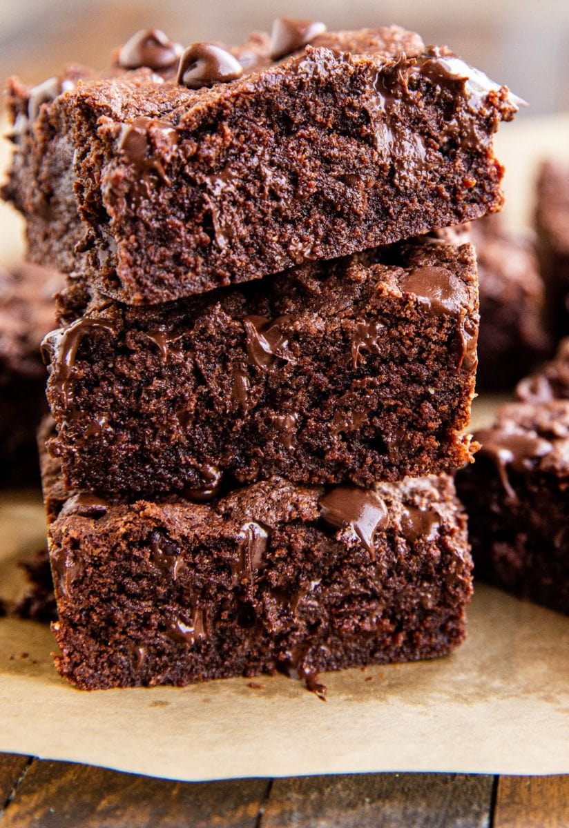Stack of three coconut flour brownies with gooey chocolate shining through.