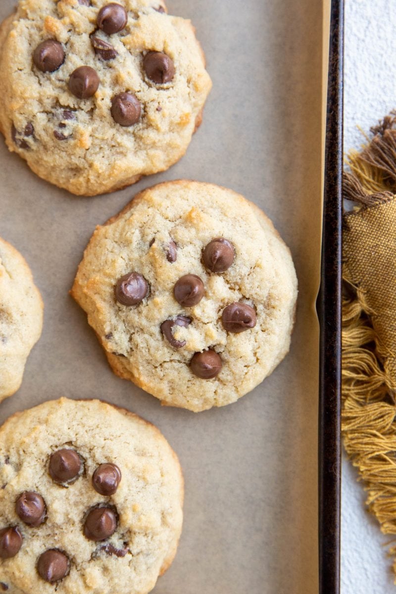 Close up top down Coconut flour chocolate chip cookies on parchment paper on a baking sheet with a napkin to the side