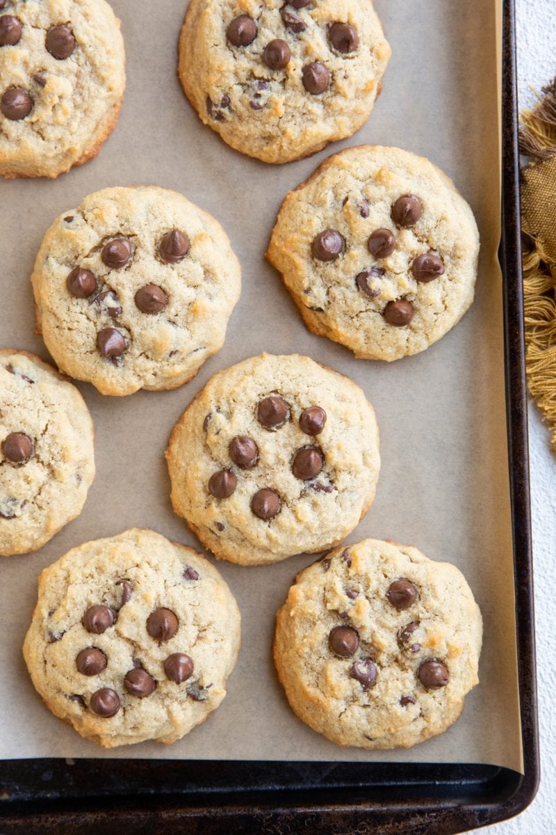 Top down photo Coconut flour chocolate chip cookies on parchment paper on a baking sheet with a napkin to the side