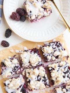 top down photo of a plate with a slice of blackberry crumb bar and slices on top of parchment paper
