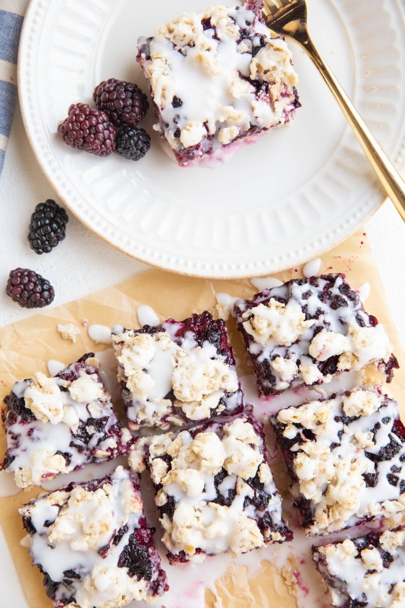 top down photo of a plate with a slice of blackberry crumb bar and slices on top of parchment paper