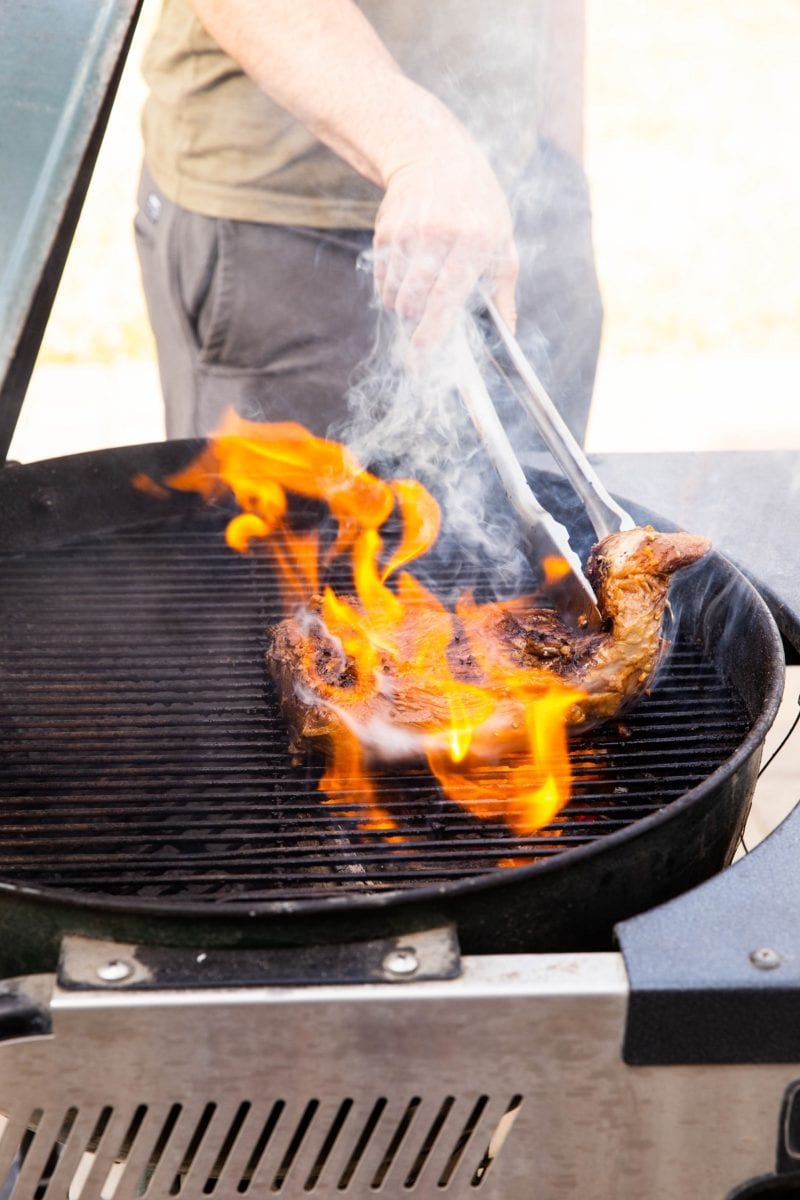 Tri tip on a charcoal grill with a large flame