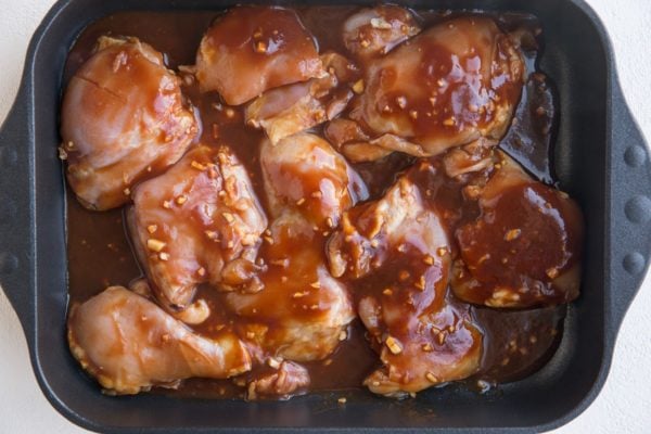 Raw marinated chicken in a casserole dish, ready to go into the oven.
