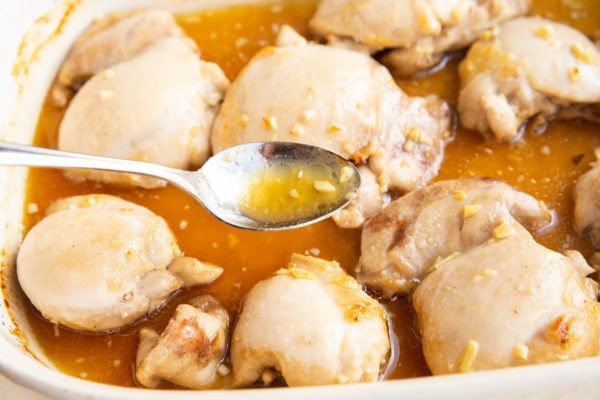 Basting chicken thighs with juices from the casserole dish