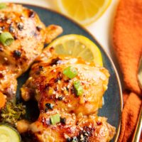 blue plate of chicken thighs and sautéed vegetables