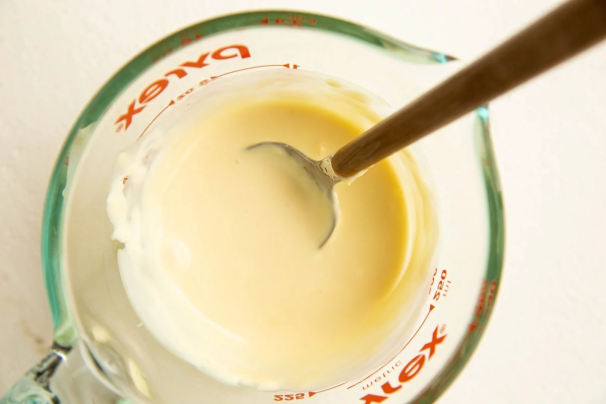Creamy honey sauce in a measuring cup
