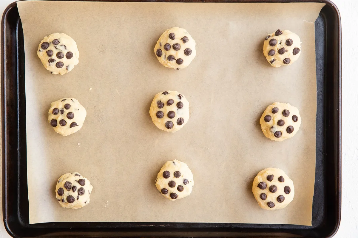 mounds of chocolate chip cookie dough on a baking sheet.