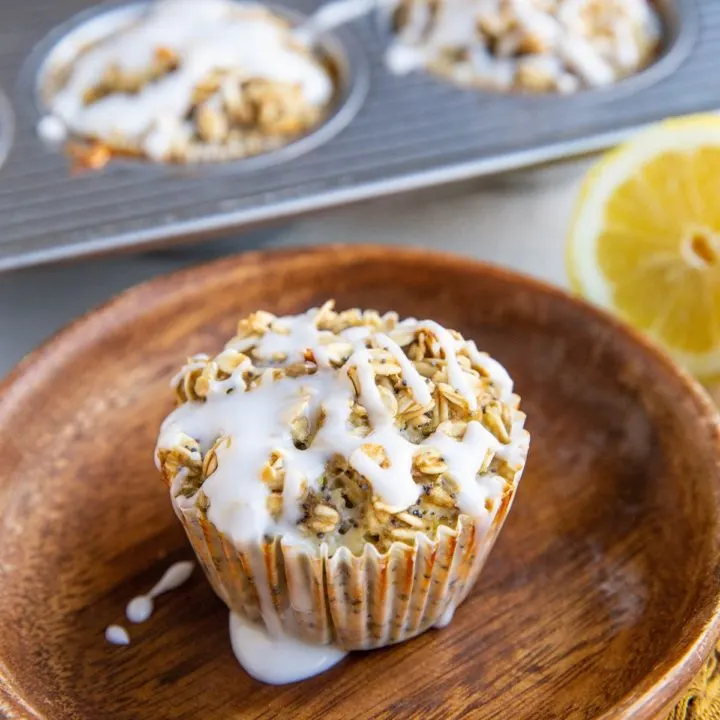Lemon poppy seed oatmeal muffin on a plate with muffins in the background
