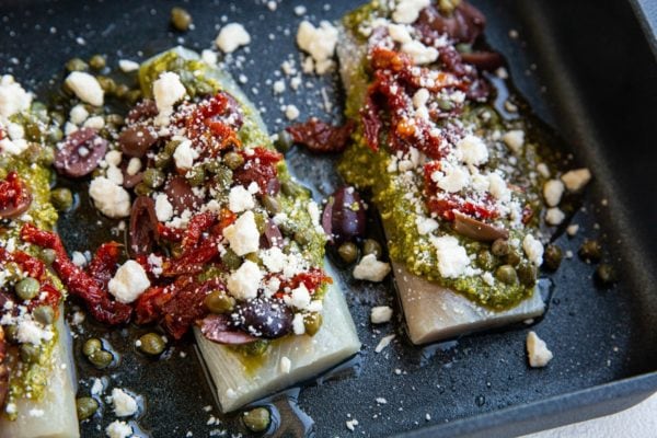 raw cod with ingredients on top ready to go into the oven