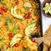 Casserole dish of chicken and rice casserole with a wooden spoon scooping some of it out.