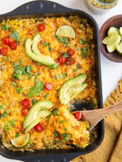 Casserole dish of chicken and rice casserole with a wooden spoon scooping some of it out.