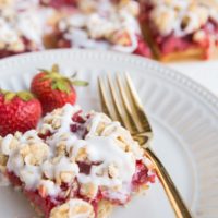 strawberry oatmeal bar on a plate with a gold fork and bars in the background